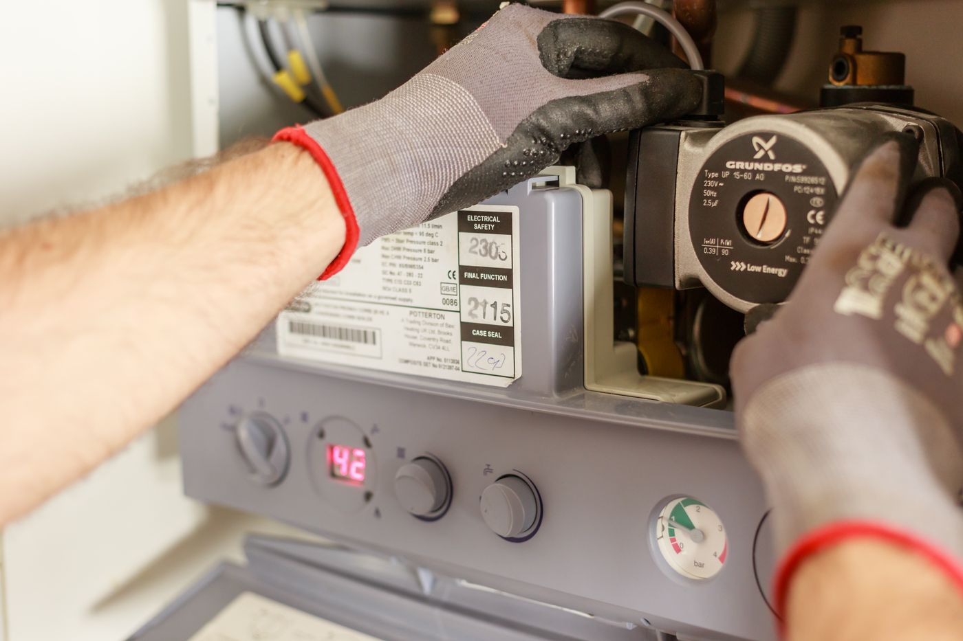 A heating engineer servicing the internal components of a domestic combi boiler.