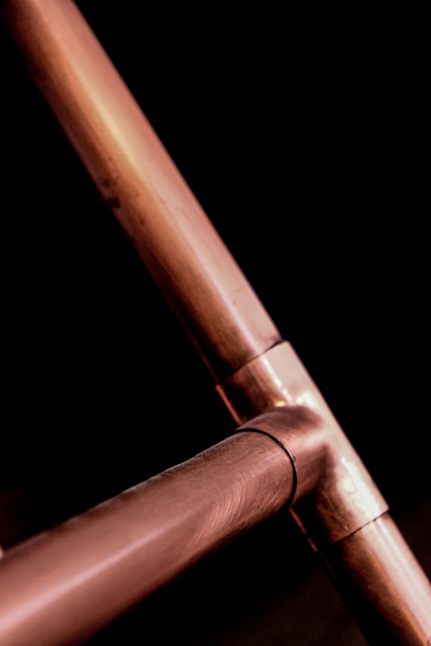 A soldered copper pipe joint against a black background.
