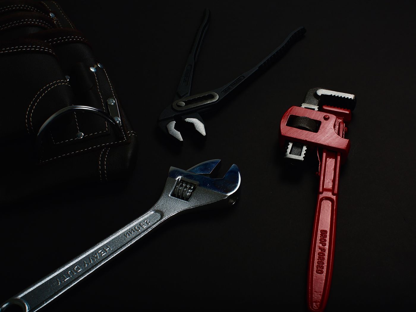 Plumbing tools laid out ready on a dark surface.